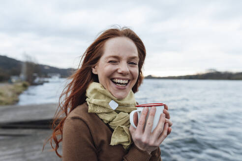 Glückliche Frau mit Teetasse am See - KNSF09784
