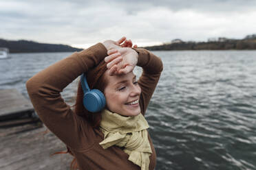 Lächelnde Frau beim Musikhören am See - KNSF09787
