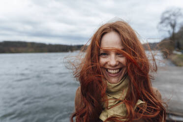 Redhead woman laughing and enjoying in front of lake - KNSF09797