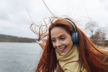 Happy redhead woman enjoying listening to music - KNSF09801