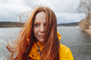 Redhead woman with long hair in front of lake - KNSF09823