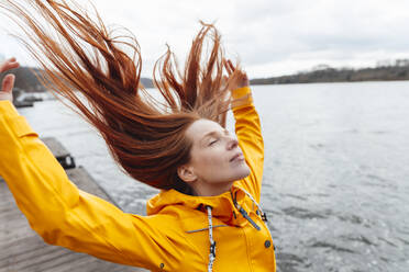 Redhead woman with tousled hair by lake - KNSF09825