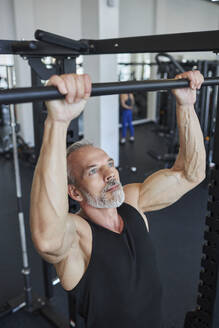 Muskulöser reifer Mann macht Klimmzüge im Fitnessstudio - KPEF00194