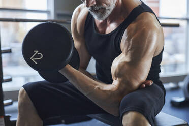 Mann mit Hantel stärkt Bizeps im Fitnessstudio - KPEF00201