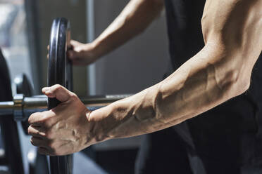 Hände eines Mannes bei der Vorbereitung einer Langhantel im Fitnessstudio - KPEF00210