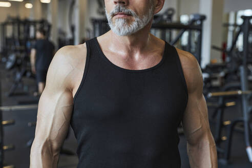 Muskulöser reifer Mann mit Bart im Fitnessstudio - KPEF00218