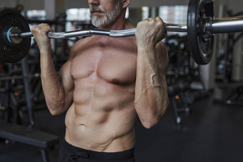 Shirtless mature man exercising with barbell in gym - KPEF00229