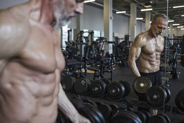 Mature man choosing dumbbell in gym - KPEF00239