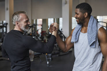 Smiling men greeting each other at gym - KPEF00248