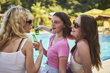 Lächelnde Freunde mit Flaschen am Swimmingpool - ANNF00423