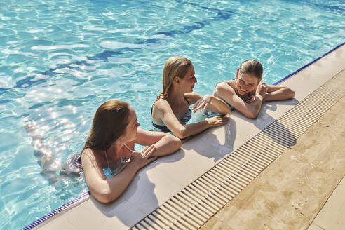 Glückliche Freunde entspannen sich am Pool an einem sonnigen Tag - ANNF00430