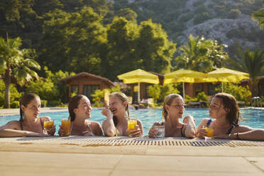 Glückliche Freunde mit Gläsern Saft feiern im Schwimmbad an einem sonnigen Tag - ANNF00434