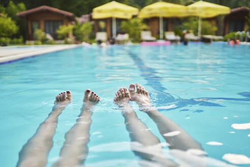 Beine einer Frau beim Schwimmen im Pool eines Ferienorts - ANNF00465
