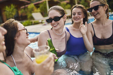 Glückliche Freunde unterhalten sich und genießen die Poolparty im Resort - ANNF00471