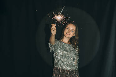 Woman holding sparkler in front of black curtain - ADF00159