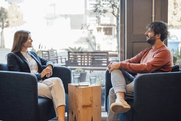 Smiling businessman people sitting on armchair and talking in office - JOSEF20580