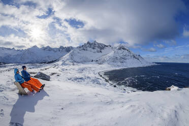 Norwegen, Troms og Finnmark, Zwei Wanderer sitzen auf einer Bank mit Blick auf den Mefjord - ANSF00487