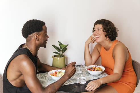 Lächelndes Paar im Gespräch und mit Salat am Esstisch - PBTF00162