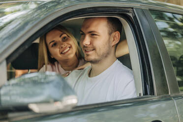 Smiling couple sitting together in car - VSNF01347