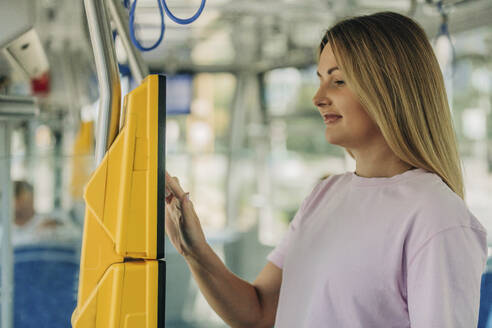 Young woman buying ticket from machine in train - VSNF01348