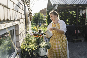 Frau bewässert Pflanzen im Garten an einem sonnigen Tag - VBUF00336