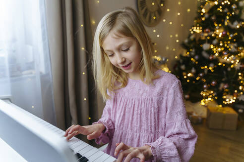 Mädchen spielt zu Hause an Weihnachten Klavier - NJAF00575