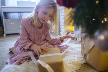 Mädchen betrachtet ein Geschenk im Weihnachtsurlaub - NJAF00577