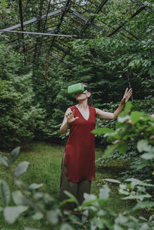 Frau mit futuristischem Headset und Gesten im Gewächshaus - YTF01090