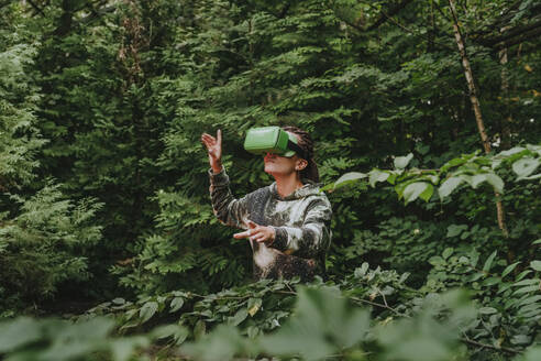 Frau mit VR-Brille beobachtet Bäume und erkundet den Wald - YTF01098