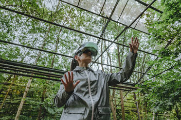 Woman with VR glasses gesturing in greenhouse - YTF01105