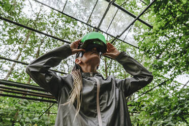 Woman watching through futuristic headset in greenhouse - YTF01106