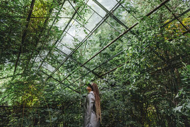 Frau beobachtet Bäume durch eine futuristische Brille im Gewächshaus - YTF01110