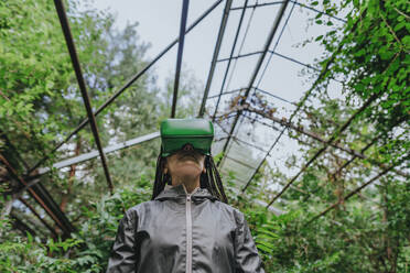 Woman wearing VR glasses in greenhouse - YTF01114