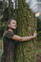 Woman hugging tree in forest - YTF01117