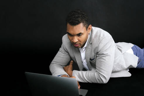 Geschäftsmann mit Laptop vor schwarzem Hintergrund - PBTF00174