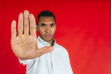 Mann macht Stop-Geste vor rotem Hintergrund - PBTF00188