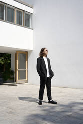 Junger Mann im Anzug steht vor einem Gebäude - EKHF00073