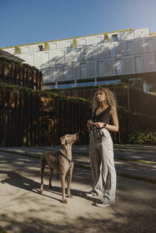 Frau und Hund stehen vor einem Gebäude - MTBF01274