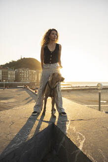 Young woman standing with dog on promenade - MTBF01278