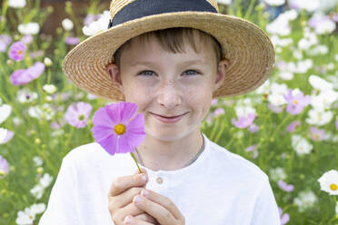 Lächelnder Junge mit Hut und Blume im Garten - VBUF00356