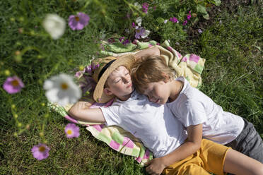 Boys relaxing on blanket in garden on sunny day - VBUF00362