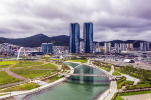 South Korea, Busan, Cloudy sky over bridge over river flowing through city park - THAF03212