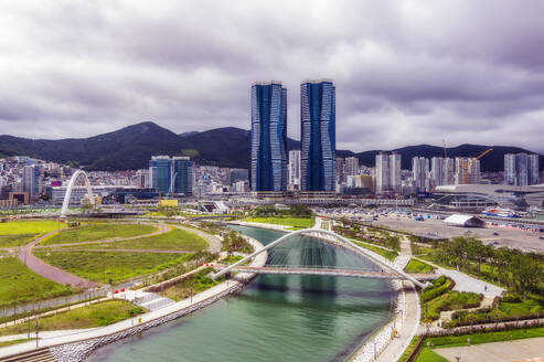South Korea, Busan, Cloudy sky over bridge over river flowing through city park - THAF03212