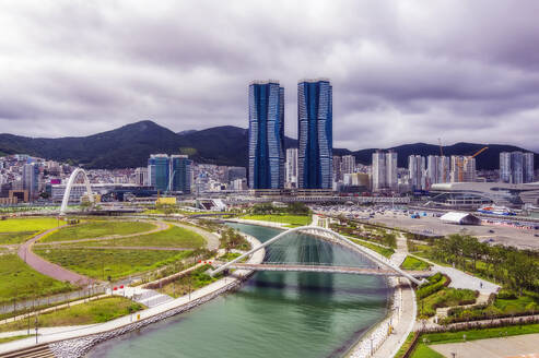 Südkorea, Busan, Bewölkter Himmel über Brücke über Fluss, der durch Stadtpark fließt - THAF03212