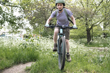 Junge Frau fährt Fahrrad auf Gras im Wald - AMWF01656