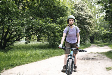 Frau fährt Fahrrad auf einem Fußweg im Wald - AMWF01658