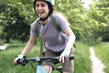 Glückliche Frau genießt das Fahrradfahren im Wald - AMWF01667