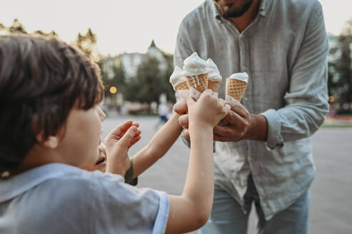 Father giving ice cream cones to sons - ANAF02021