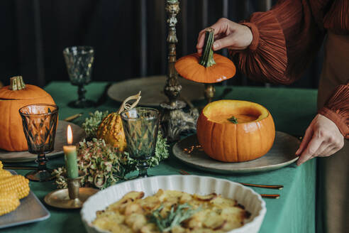 Frau serviert Kürbissuppe für Thanksgiving Abendessen am Esstisch - VSNF01358