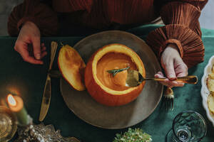 Woman having pumpkin soup at dining table - VSNF01359